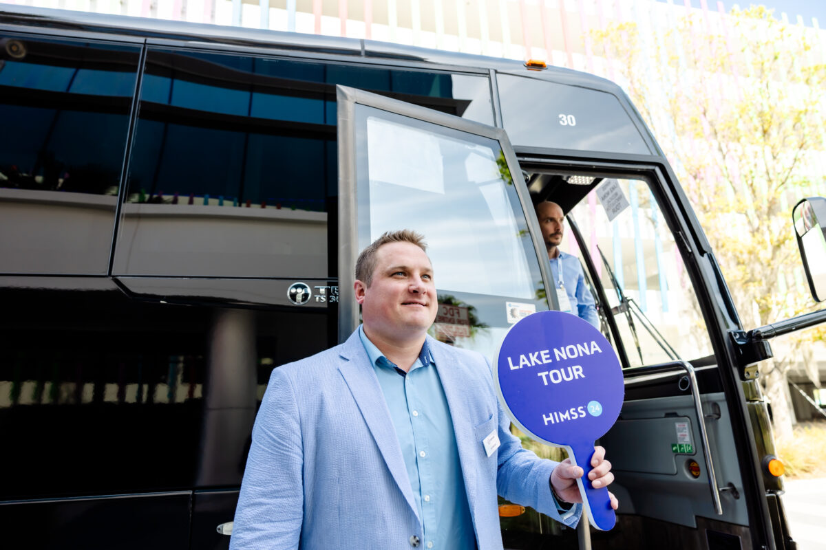 Lee Marana holds a lollipop sign welcoming Lake Nona tour attendees