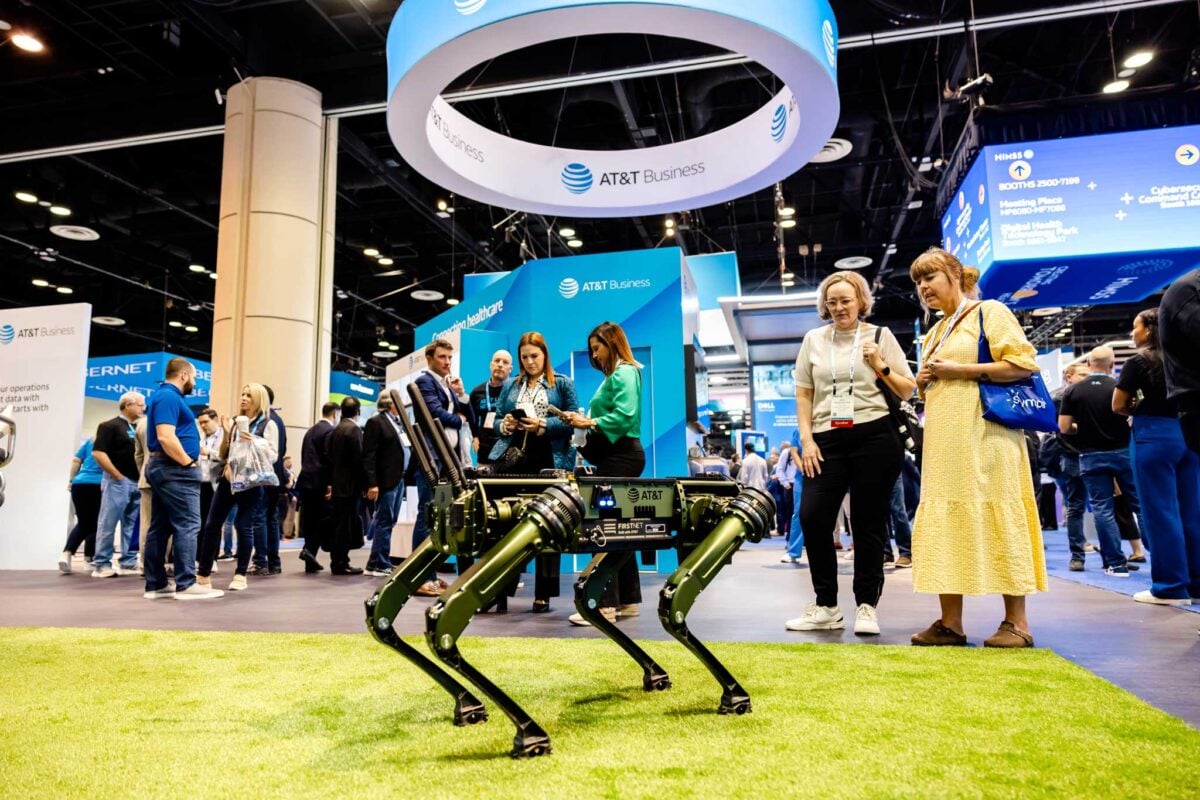 Attendees at the HIMSS Global Health Conference exploring a robotic technology exhibit at the AT&T Business booth.
